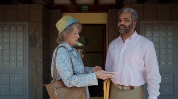 Movie still from “The Laundromat” (2019), directed by Steven Soderbergh – An older man and a younger woman standing next to each other; Medium shot, Over the shoulder angle