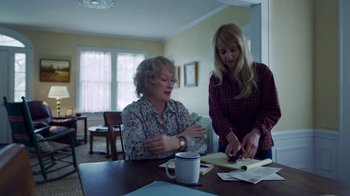 Movie still from “The Laundromat” (2019), directed by Steven Soderbergh – Two women looking at a book on a table; Medium shot, Over the shoulder angle