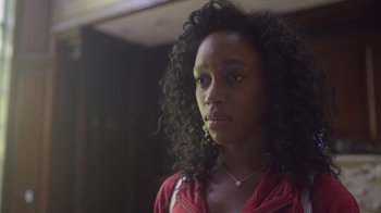 Movie still from “The Laundromat” (2019), directed by Steven Soderbergh – A young woman with curly black hair wearing a red jacket; Close Up shot, Low angle