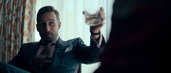 Movie still from “The Laundromat” (2019), directed by Steven Soderbergh – A man in a striped suit holding a tooth brush in his hand; Close Up shot, Over the shoulder angle