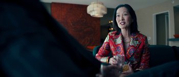 Movie still from “The Laundromat” (2019), directed by Steven Soderbergh – A woman sitting at a table with a glass of wine; Medium shot, Over the shoulder angle
