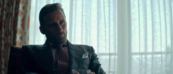 Movie still from “The Laundromat” (2019), directed by Steven Soderbergh – A man wearing a suit and tie holding a glass; Close Up shot, Over the shoulder angle