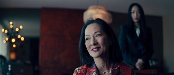 Movie still from “The Laundromat” (2019), directed by Steven Soderbergh – An older asian woman in a colorful shirt; Close Up shot, Over the shoulder angle