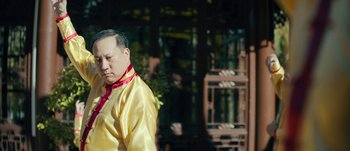 Movie still from “The Laundromat” (2019), directed by Steven Soderbergh – An older man in a yellow shirt and a red tie; Medium shot, Low angle
