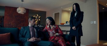 Movie still from “The Laundromat” (2019), directed by Steven Soderbergh – Two women and a man are sitting on a couch; Medium shot, Over the shoulder angle