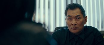 Movie still from “The Laundromat” (2019), directed by Steven Soderbergh – A person sitting in front of a window; Close Up shot, Over the shoulder angle