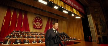 Movie still from “The Laundromat” (2019), directed by Steven Soderbergh – A man standing at a podium with microphones; Medium shot, Low angle