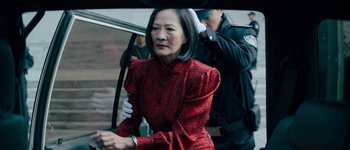 Movie still from “The Laundromat” (2019), directed by Steven Soderbergh – An older woman in a red dress is getting out of a car; Medium shot, Over the shoulder angle