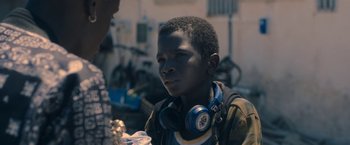 Movie still from “The Life Ahead” (2020), directed by Edoardo Ponti – A young man wearing headphones and looking at a person; Close Up shot, Over the shoulder angle