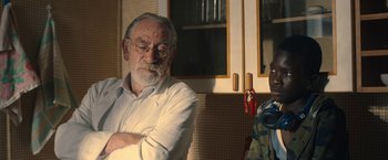 Movie still from “The Life Ahead” (2020), directed by Edoardo Ponti – An older man and a younger man are sitting in a kitchen; Medium shot, Over the shoulder angle