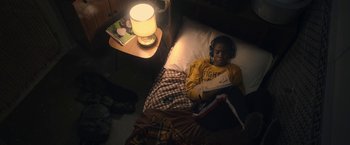 Movie still from “The Life Ahead” (2020), directed by Edoardo Ponti – A young boy laying in a bed reading a book; Medium shot, Overhead angle