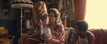 Movie still from “The Life Ahead” (2020), directed by Edoardo Ponti – Two women sitting in a living room one holding a bag of candy; Medium shot, Over the shoulder angle