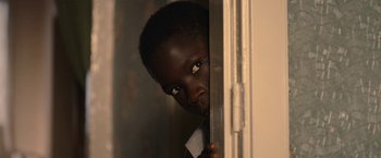 Movie still from “The Life Ahead” (2020), directed by Edoardo Ponti – A young black man peeking out of a window; Close Up shot, High angle