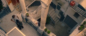 Movie still from “The Life Ahead” (2020), directed by Edoardo Ponti – An aerial view looking down at a building with a pillar and steps; Extreme Wide shot, High angle