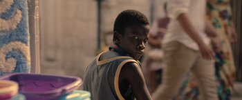Movie still from “The Life Ahead” (2020), directed by Edoardo Ponti – A young boy is standing in front of some people; Close Up shot, Over the shoulder angle