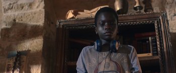 Movie still from “The Life Ahead” (2020), directed by Edoardo Ponti – A young boy wearing headphones in front of a book case; Close Up shot, Over the shoulder angle