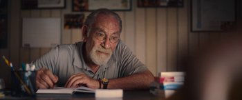 Movie still from “The Life Ahead” (2020), directed by Edoardo Ponti – An older man sitting at a table in front of papers; Close Up shot, Over the shoulder angle