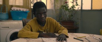 Movie still from “The Life Ahead” (2020), directed by Edoardo Ponti – A young man sitting at a table with a book; Close Up shot, Over the shoulder angle