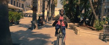 Movie still from “The Life Ahead” (2020), directed by Edoardo Ponti – A young man riding a bike down a sidewalk; Medium shot, Low angle
