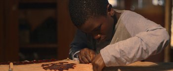Movie still from “The Life Ahead” (2020), directed by Edoardo Ponti – A young man working on a piece of paper; Close Up shot, High angle
