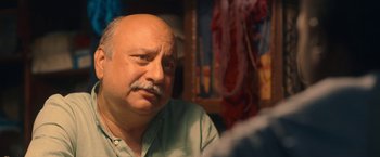 Movie still from “The Life Ahead” (2020), directed by Edoardo Ponti – An older man with a shaved head is sitting at a table; Close Up shot, Over the shoulder angle