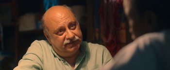 Movie still from “The Life Ahead” (2020), directed by Edoardo Ponti – An older man with a mustache looking at the camera; Close Up shot, Over the shoulder angle