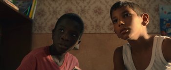 Movie still from “The Life Ahead” (2020), directed by Edoardo Ponti – Two young children are standing together in a room; Close Up shot, Low angle