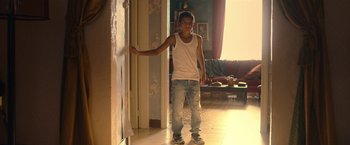 Movie still from “The Life Ahead” (2020), directed by Edoardo Ponti – A young man standing in a room next to a wall; Medium shot, Low angle
