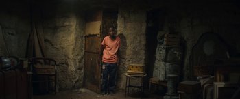 Movie still from “The Life Ahead” (2020), directed by Edoardo Ponti – A man standing in front of a door way; Wide shot, Low angle