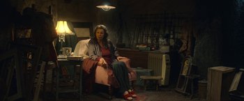 Movie still from “The Life Ahead” (2020), directed by Edoardo Ponti – A woman sitting in a chair in a room; Wide shot, High angle