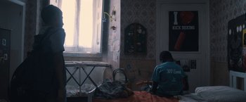 Movie still from “The Life Ahead” (2020), directed by Edoardo Ponti – A person sitting on a bed playing a guitar; Wide shot, High angle