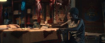 Movie still from “The Life Ahead” (2020), directed by Edoardo Ponti – A young boy sitting at a table in a room; Medium shot, High angle