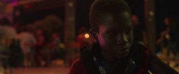 Movie still from “The Life Ahead” (2020), directed by Edoardo Ponti – A young boy wearing headphones and a red jacket; Close Up shot, Over the shoulder angle