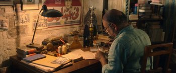 Movie still from “The Life Ahead” (2020), directed by Edoardo Ponti – A man sitting at a desk writing on a piece of paper; Medium shot, High angle