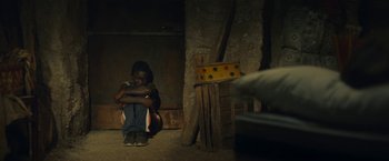 Movie still from “The Life Ahead” (2020), directed by Edoardo Ponti – A person sitting on the ground with their arms crossed; Medium shot, High angle