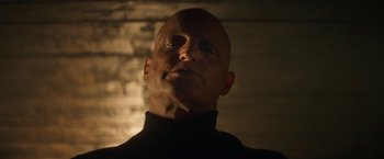 Movie still from “The Man from Toronto” (2022), directed by Patrick Hughes – A bald man in a black shirt is looking up; Close Up shot, Low angle