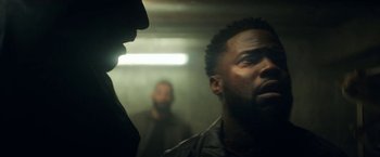 Movie still from “The Man from Toronto” (2022), directed by Patrick Hughes – Two men are standing in a dark room looking at each other; Close Up shot, Over the shoulder angle