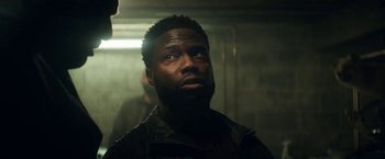 Movie still from “The Man from Toronto” (2022), directed by Patrick Hughes – A man in a black jacket is looking at the camera; Close Up shot, Over the shoulder angle