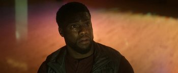 Movie still from “The Man from Toronto” (2022), directed by Patrick Hughes – A person wearing a jacket and looking at the camera; Close Up shot, Over the shoulder angle