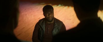 Movie still from “The Man from Toronto” (2022), directed by Patrick Hughes – A man sitting in front of a projection screen; Medium shot, Over the shoulder angle