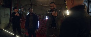 Movie still from “The Man from Toronto” (2022), directed by Patrick Hughes – Two men are standing in front of one another holding a gun; Medium shot, Over the shoulder angle