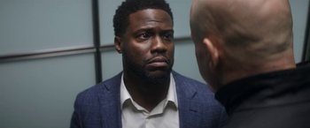 Movie still from “The Man from Toronto” (2022), directed by Patrick Hughes – A person wearing a suit and a tie; Close Up shot, Over the shoulder angle