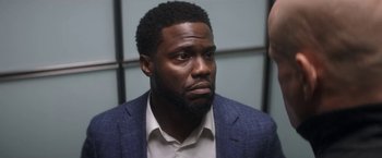 Movie still from “The Man from Toronto” (2022), directed by Patrick Hughes – A person wearing a suit and tie; Close Up shot, Over the shoulder angle