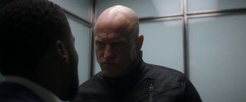 Movie still from “The Man from Toronto” (2022), directed by Patrick Hughes – A man with a bald head in an elevator; Close Up shot, Low angle