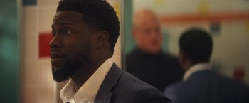 Movie still from “The Man from Toronto” (2022), directed by Patrick Hughes – A man wearing a suit and tie in front of another man; Close Up shot, Over the shoulder angle