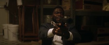 Movie still from “The Man from Toronto” (2022), directed by Patrick Hughes – A man holding a cell phone up to the camera; Close Up shot, Over the shoulder angle