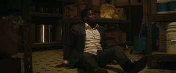 Movie still from “The Man from Toronto” (2022), directed by Patrick Hughes – A man sitting on the ground in a room; Medium shot, High angle