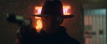 Movie still from “The Man from Toronto” (2022), directed by Patrick Hughes – A man wearing a hat standing in front of a neon sign; Close Up shot, Low angle
