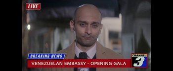 Movie still from “The Man from Toronto” (2022), directed by Patrick Hughes – A man in a suit and tie standing in front of a news sign; Close Up shot, Low angle