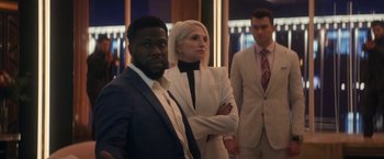 Movie still from “The Man from Toronto” (2022), directed by Patrick Hughes – Two men and a woman standing next to each other in suits; Medium shot, Over the shoulder angle